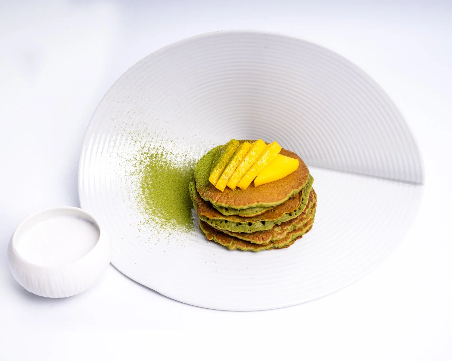 Matcha Spinach Pancakes — Green stack with fresh mango and coconut yoghurt.